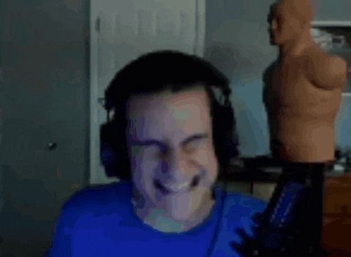 a man wearing headphones and a blue shirt is standing in front of a boxing dummy