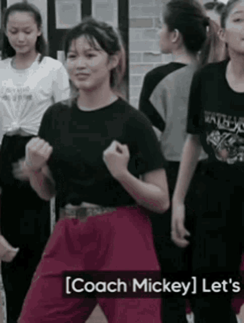 a girl in a black shirt and red pants is dancing in front of a group of people .
