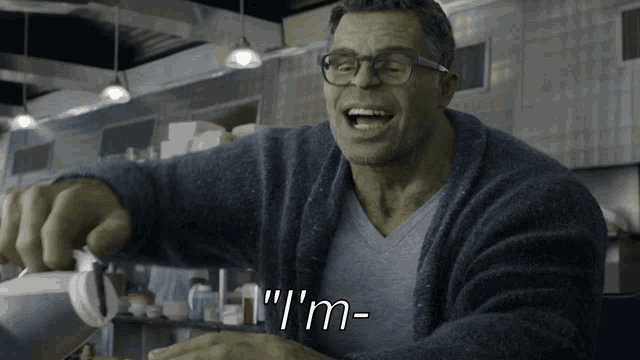 a man wearing glasses and a blue sweater says " i 'm " in white letters