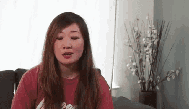 a woman in a red shirt is sitting on a couch in a living room .