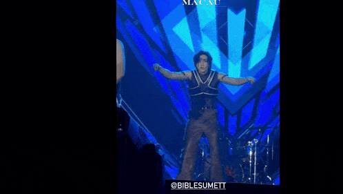 a man is jumping in the air on a stage in front of a drum set and a sign that says " biblesumett "