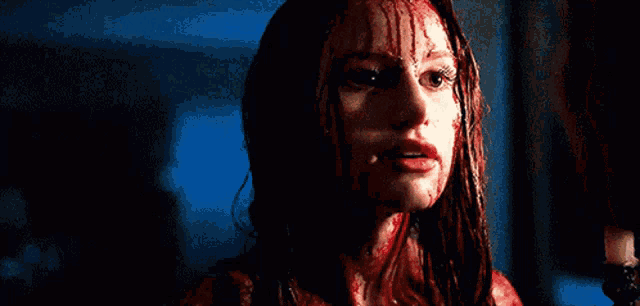 a woman with blood on her face is standing in the dark .
