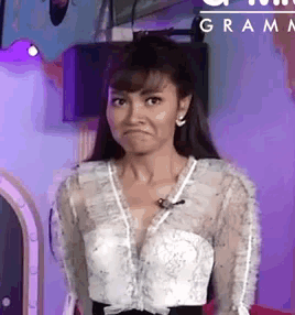 a woman is making a funny face while standing in front of a purple wall .
