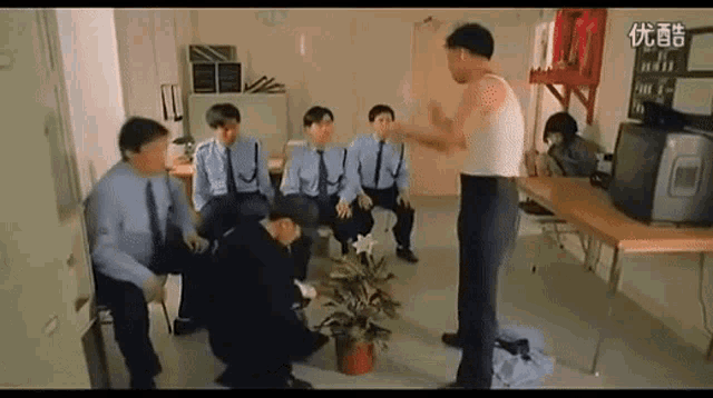 a group of men are sitting around a table and a man is standing in a room .