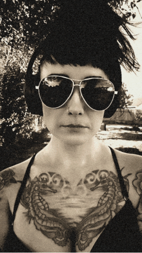 a woman wearing headphones and sunglasses has a tattoo on her chest