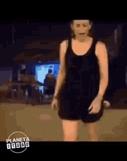 a woman in a black tank top and shorts is standing in front of a building .