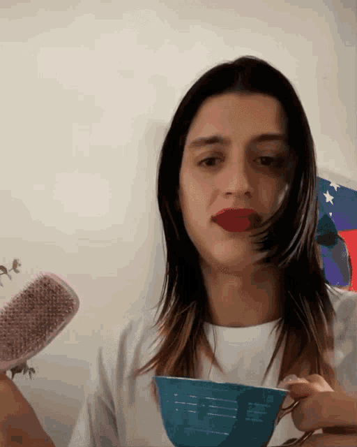 a woman with red lipstick is holding a brush and a bowl