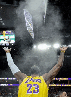 a man wearing a lakers jersey is raising his arms in the air