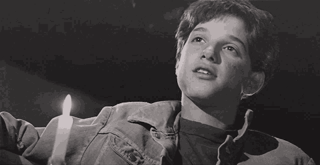 a black and white photo of a young boy holding a candle