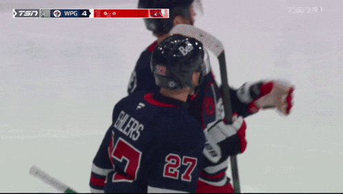 a hockey player with the number 27 on his jersey stands next to another player