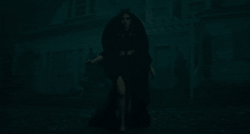 a woman carrying a child in front of a house with fireworks going off