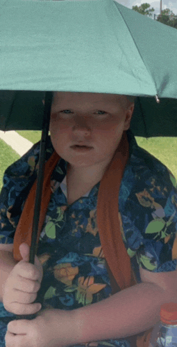 a boy in a hawaiian shirt is holding an umbrella