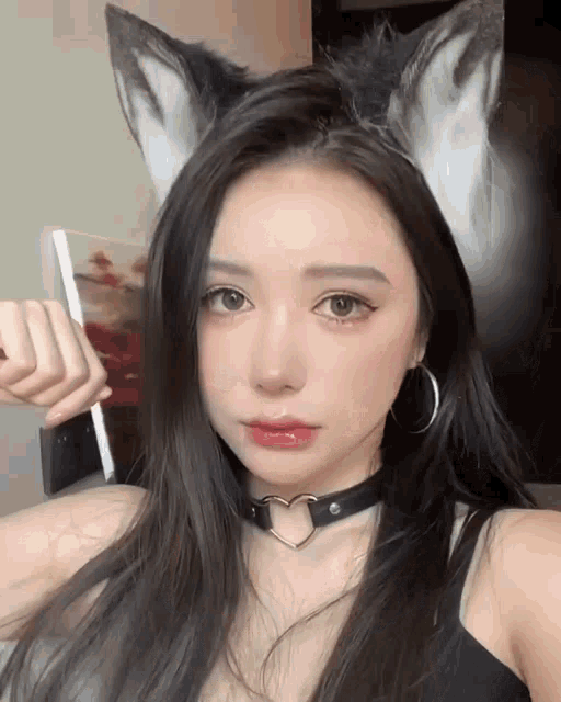 a woman wearing fox ears and a heart shaped choker is taking a selfie
