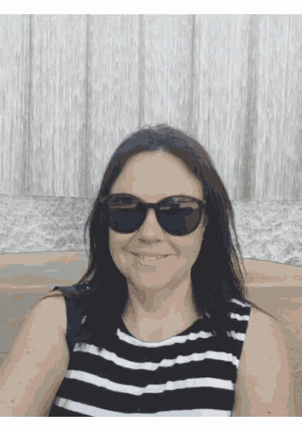 a woman wearing sunglasses and a striped shirt smiles