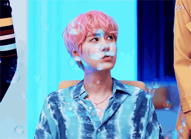 a young man with pink hair is surrounded by bubbles