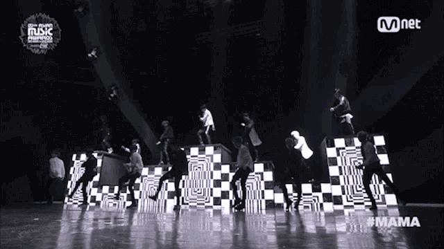 a group of people dancing on a stage in front of a sign that says mnet