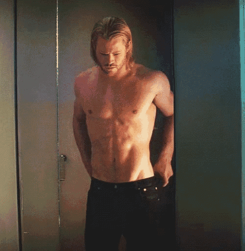 a shirtless man is leaning against a wall in a dressing room .