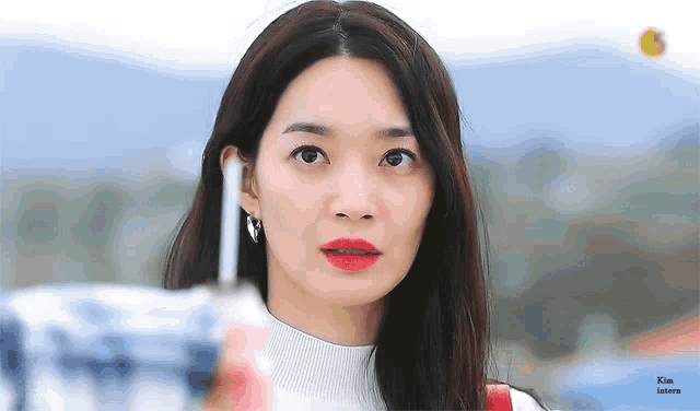 a close up of a woman wearing red lipstick and a white sweater .