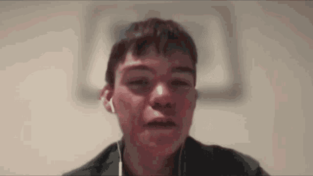 a close up of a young man wearing headphones and looking at the camera .