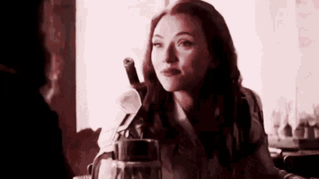 a woman is sitting at a table holding a glass of wine and a bottle of wine .