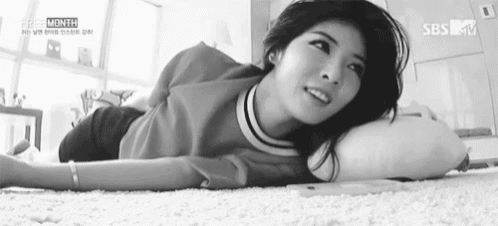 a black and white photo of a woman laying on her stomach on a carpet .