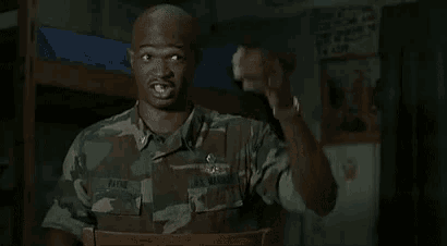 a man in a military uniform is sitting in a chair and pointing at something .
