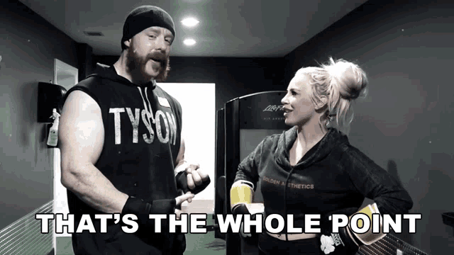 a man in a tyson shirt is talking to a woman in a gym