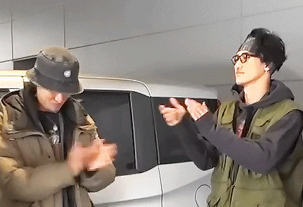 two men are standing next to each other clapping their hands in front of a white van .