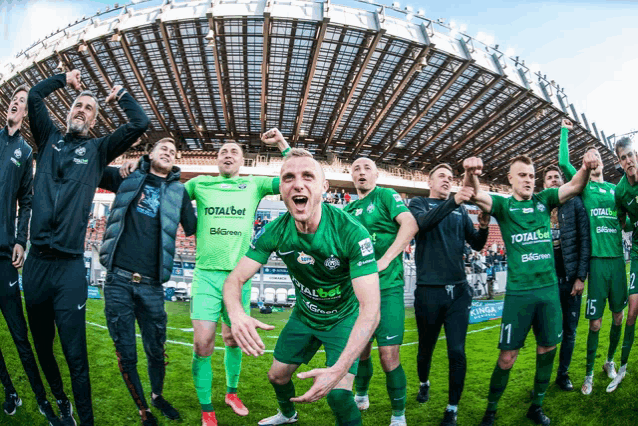a group of soccer players wearing green uniforms with totalbet on them