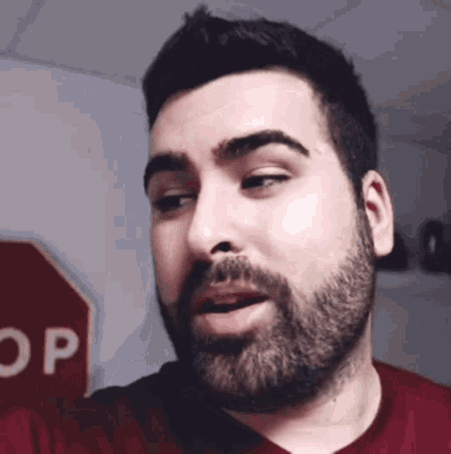 a man with a beard and a stop sign behind him