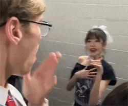 a man wearing glasses and a tie is talking to a woman in a room .