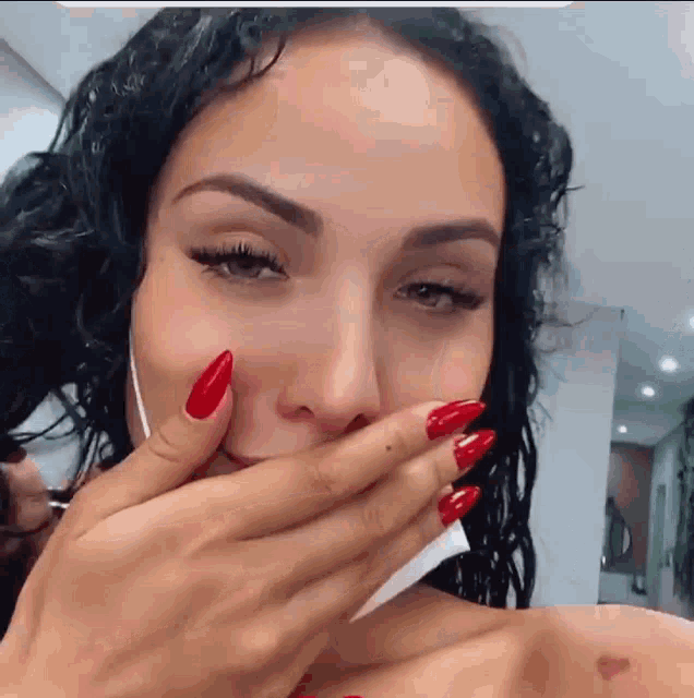 a woman with red nails covering her mouth with her hands