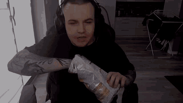 a man wearing headphones holds a bag of chips