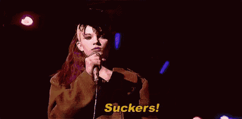 a woman is singing into a microphone and says suckers !