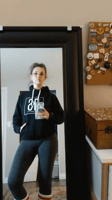 a woman taking a selfie in front of a mirror with stickers on the wall including one that says advisory