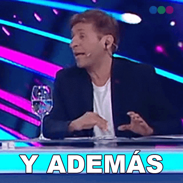 a man sitting at a table with a sign that says y ademas on it