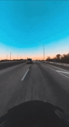 a car is driving down a highway with a sunset in the background