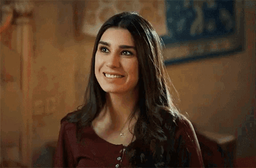 a woman in a red shirt is smiling and looking at the camera
