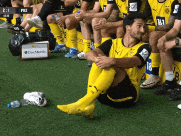 a group of soccer players are sitting on a bench and one of them has the number 18 on his shirt