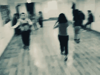 a blurry photo of people walking down a hallway .