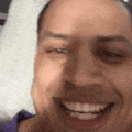 a close up of a person 's face smiling with a purple shirt on .