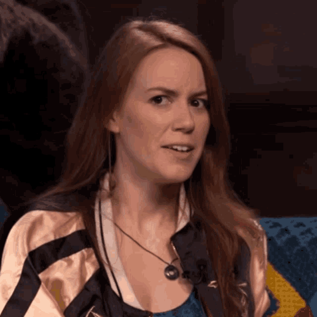 a woman with long red hair is wearing a jacket with the letter n on the front