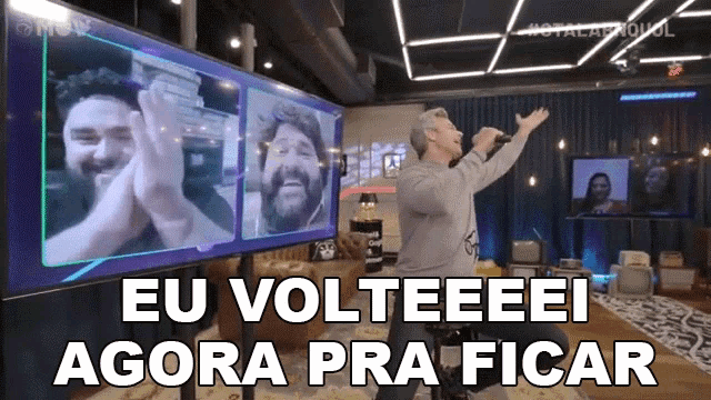 a man is singing into a microphone in front of a large screen that says eu volteeeei agora pra ficar .