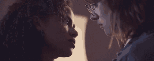 two women are kissing each other in a dark room .