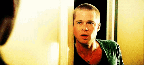 a man with a shaved head is peeking out from behind a wall