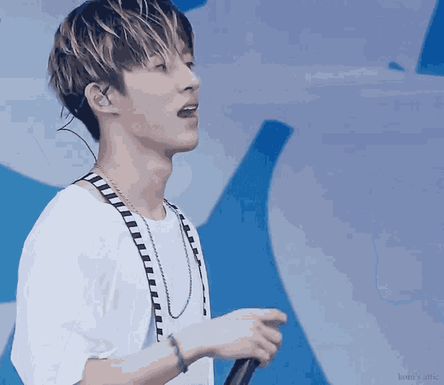 a young man singing into a microphone with the word kon 's attic written on the bottom