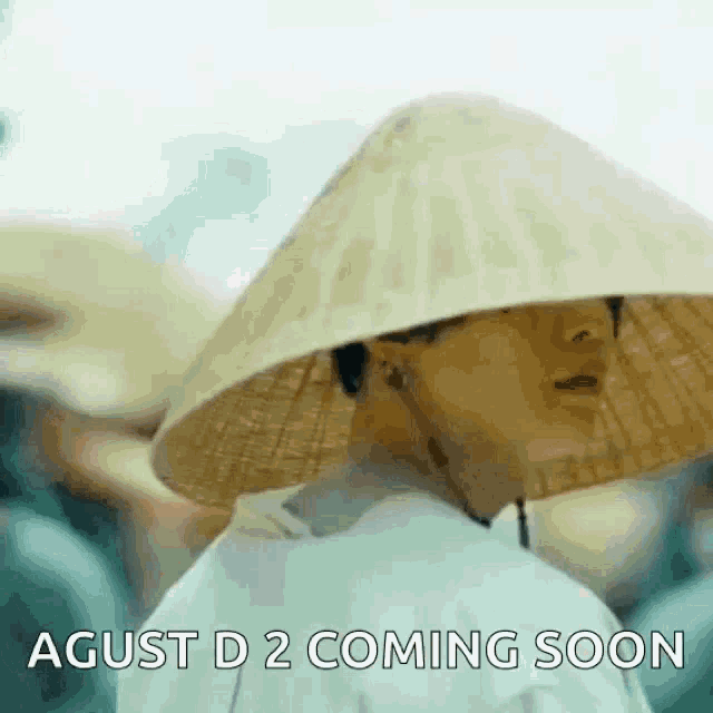 a man wearing a conical hat with the words `` agust d 2 coming soon '' on it .