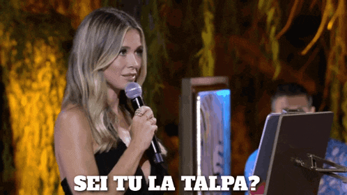 a woman speaking into a microphone with the words sei tu la talpa written below her