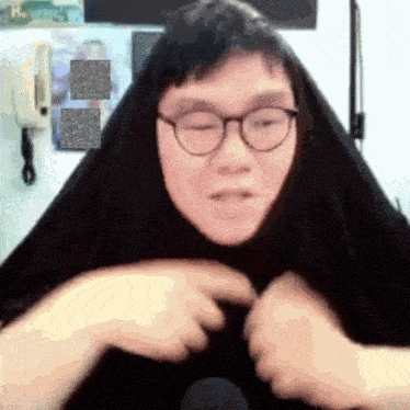 a man wearing glasses and a black scarf looks at the camera