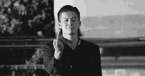 a man in a suit is giving the middle finger in a black and white photo .